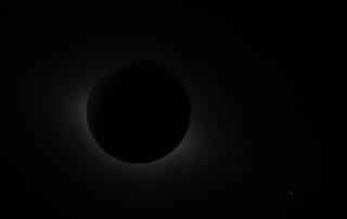 Total solar eclipse: the Moon blocks the Sun, with a faint solar corona around the edge.