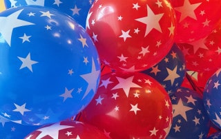 Cluster of red and blue balloons with white stars, creating a festive patriotic display.