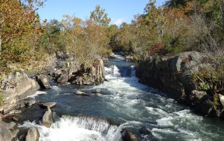 river16 | Ann Albers Visions of Heaven Autumnal river winds through a rocky gorge with small waterfalls and colorful trees along the banks.